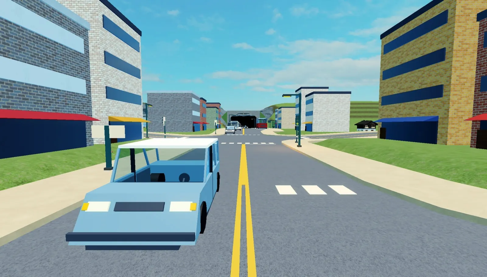 A city avenue with traffic: a light blue car in front, office blocks on both sides and a tunnel at the end